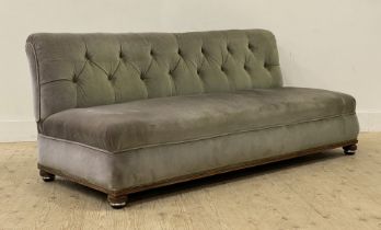 A late Victorian upholstered banquet or bench sofa, covered in deep buttoned green velvet, raised on