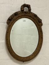 An Edwardian carved giltwood and gesso wall hanging mirror of oval outline, the frame with floral