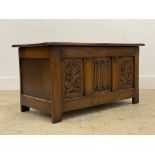 A 20th century oak blanket box, hinged lid with plain interior behind, three panel front carved in