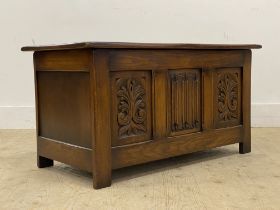 A 20th century oak blanket box, hinged lid with plain interior behind, three panel front carved in