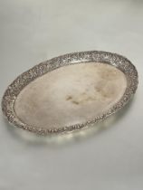 A continental white metal oval serving dish with chased floral and leaf raised border marks rubbed H