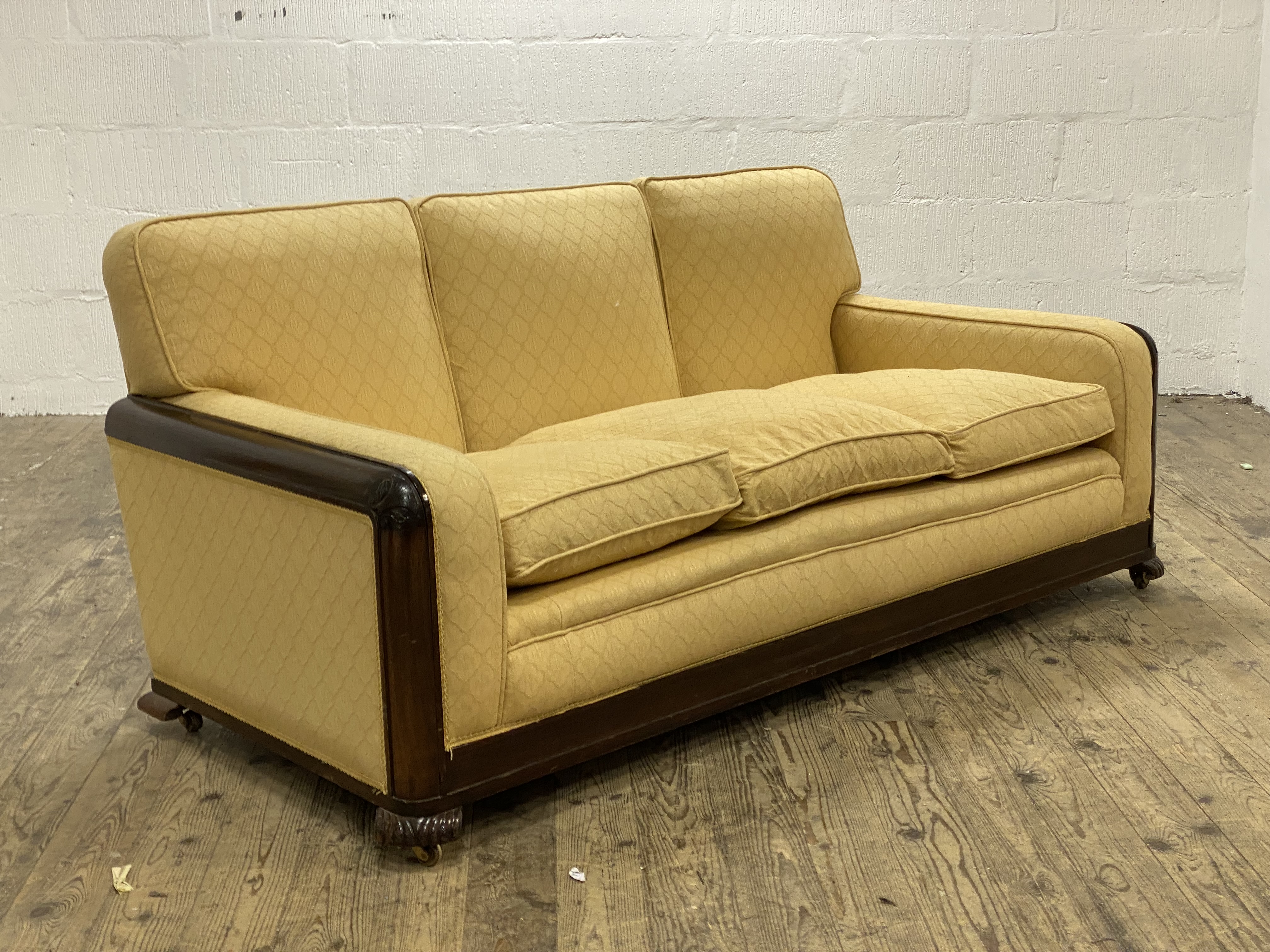 A mahogany framed three seat sofa, circa 1920's, the frame and squab cushions upholstered in