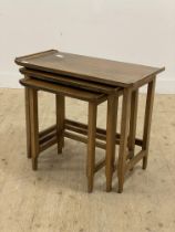 A mid 20th century walnut nest of three tables, each with a rectangular tray top raised on square