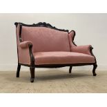 A late Victorian two seat sofa, the floral carved mahogany show frame enclosing pink damask