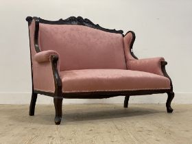 A late Victorian two seat sofa, the floral carved mahogany show frame enclosing pink damask