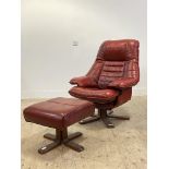 A mid century Scandinavian style reclining chair upholstered in oxblood leather and raised on a