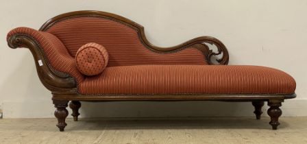 A Victorian mahogany framed chaise lounge with floral and pierce carved show frame enclosing red and