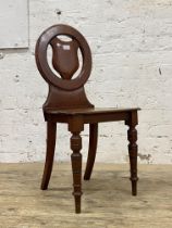 A late Victorian mahogany hall chair, the circular back with pierce carved cartouche, above a