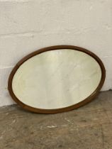 An Edwardian mahogany framed oval wall hanging mirror with bevelled glass. 77cm x 51cm.