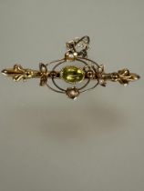 A Edwardian 9ct gold bar brooch set central oval faceted peridot on rub over setting a double halo