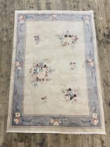 A Chinese washed wool rug, the pale field with floral bouquets within a blue border. 245cm x 165cm.
