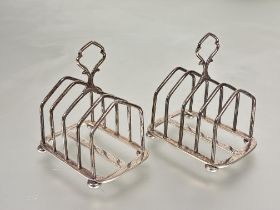 A pair of Birmingham silver four division arched toast racks with handles to top raised on bun