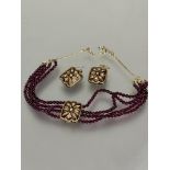 An Indian style ruby enamel and paste set necklace with pair of matching earrings, the necklace