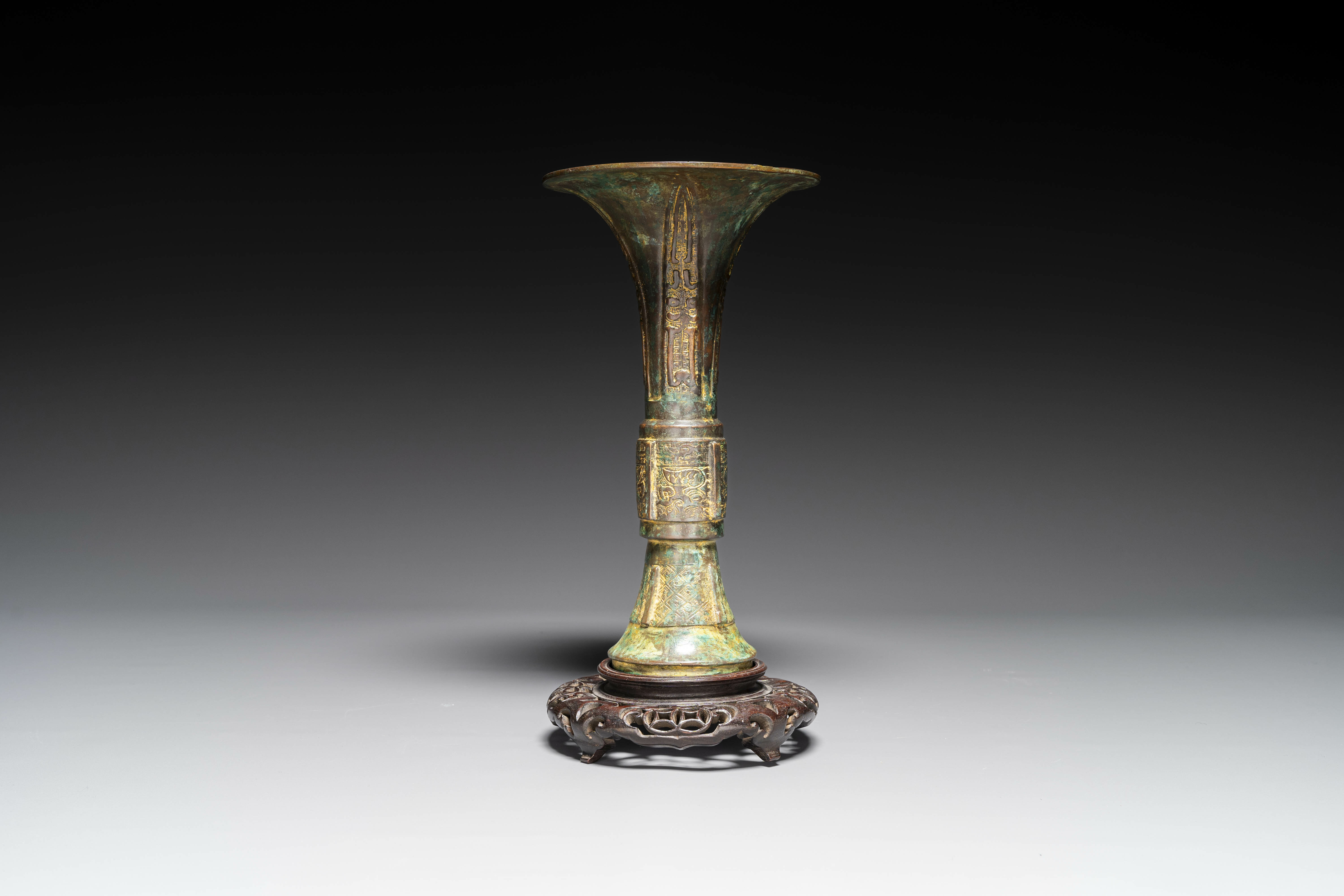 A Chinese bronze Shang-style 'gu' vase on wooden stand, 19/20th C.