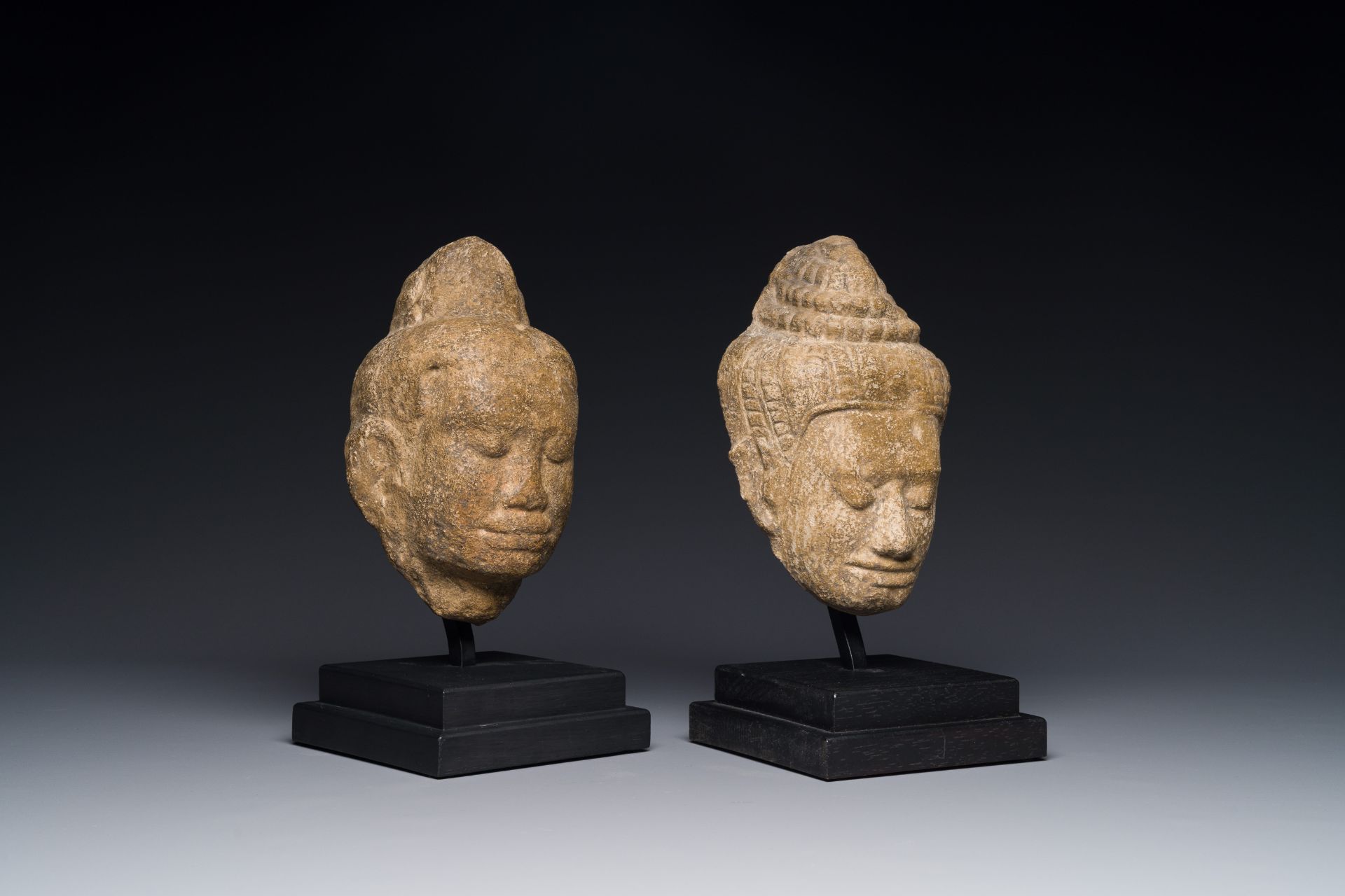 A stone head of Buddha and a sandstone khmer head of a deity, Bayon style, Cambodia, 12/13th C.