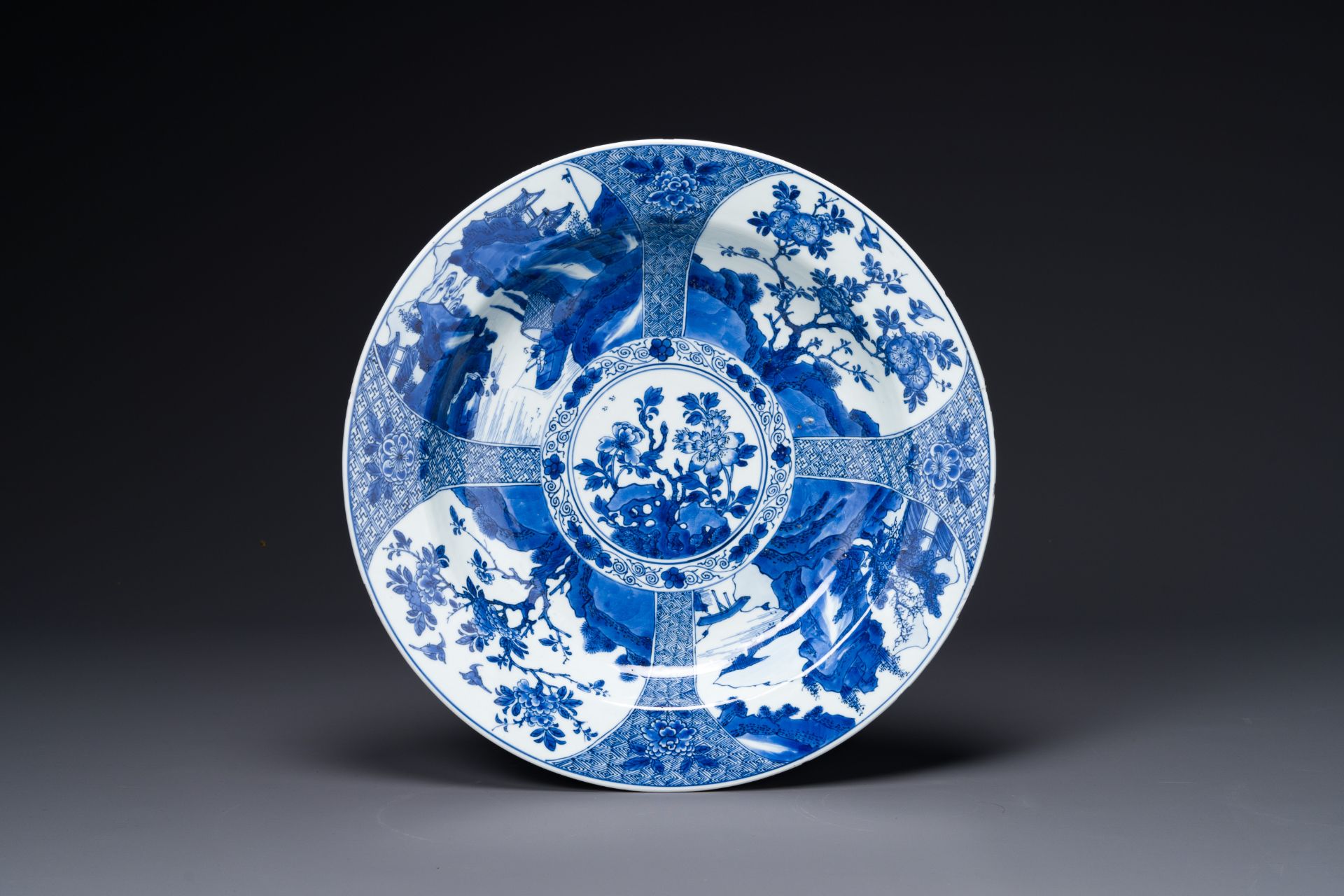 A Chinese blue and white dish with landscape and floral panels, Kangxi