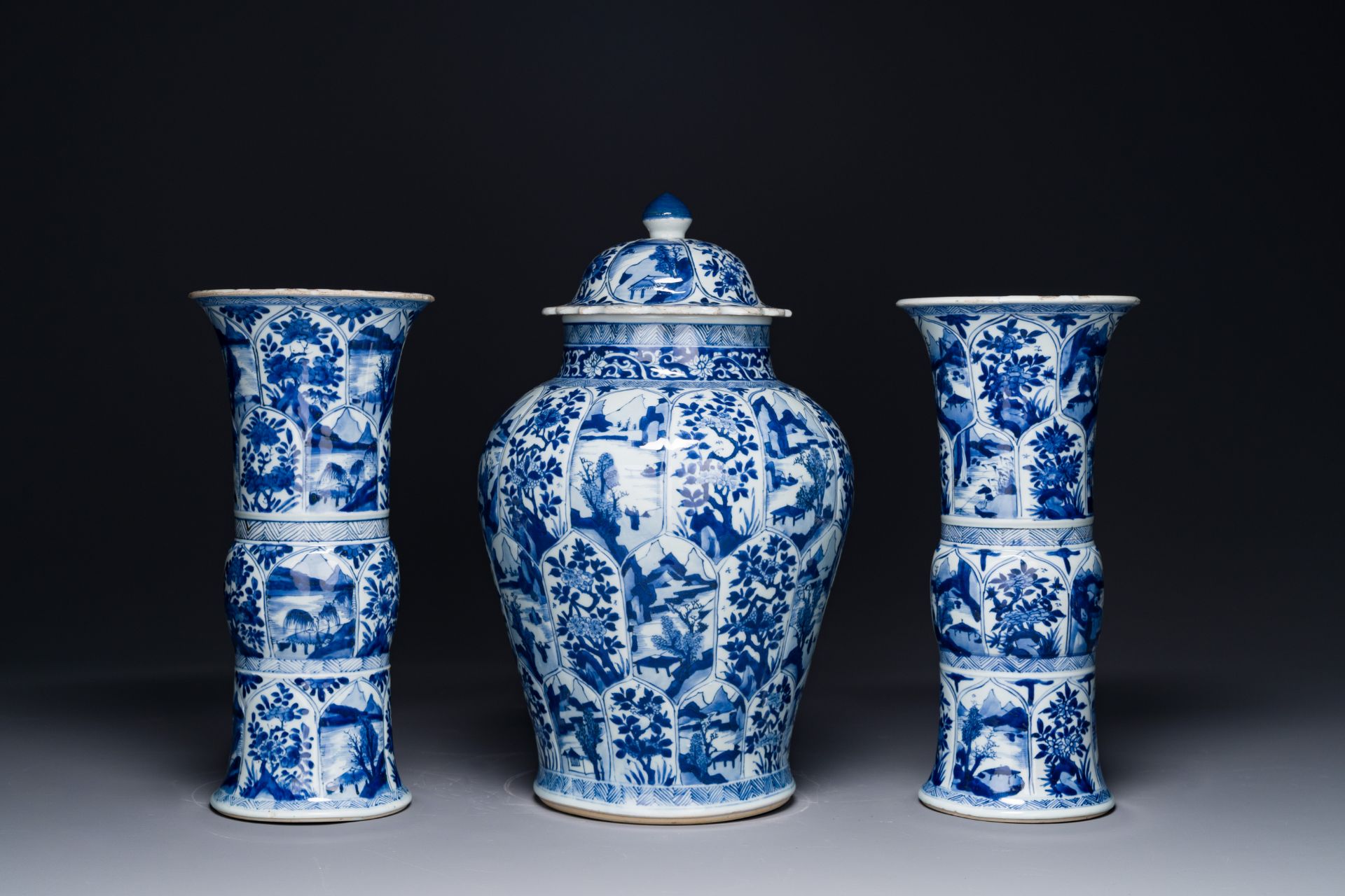 A Chinese blue and white garniture of three vases with floral and landscape design, Kangxi