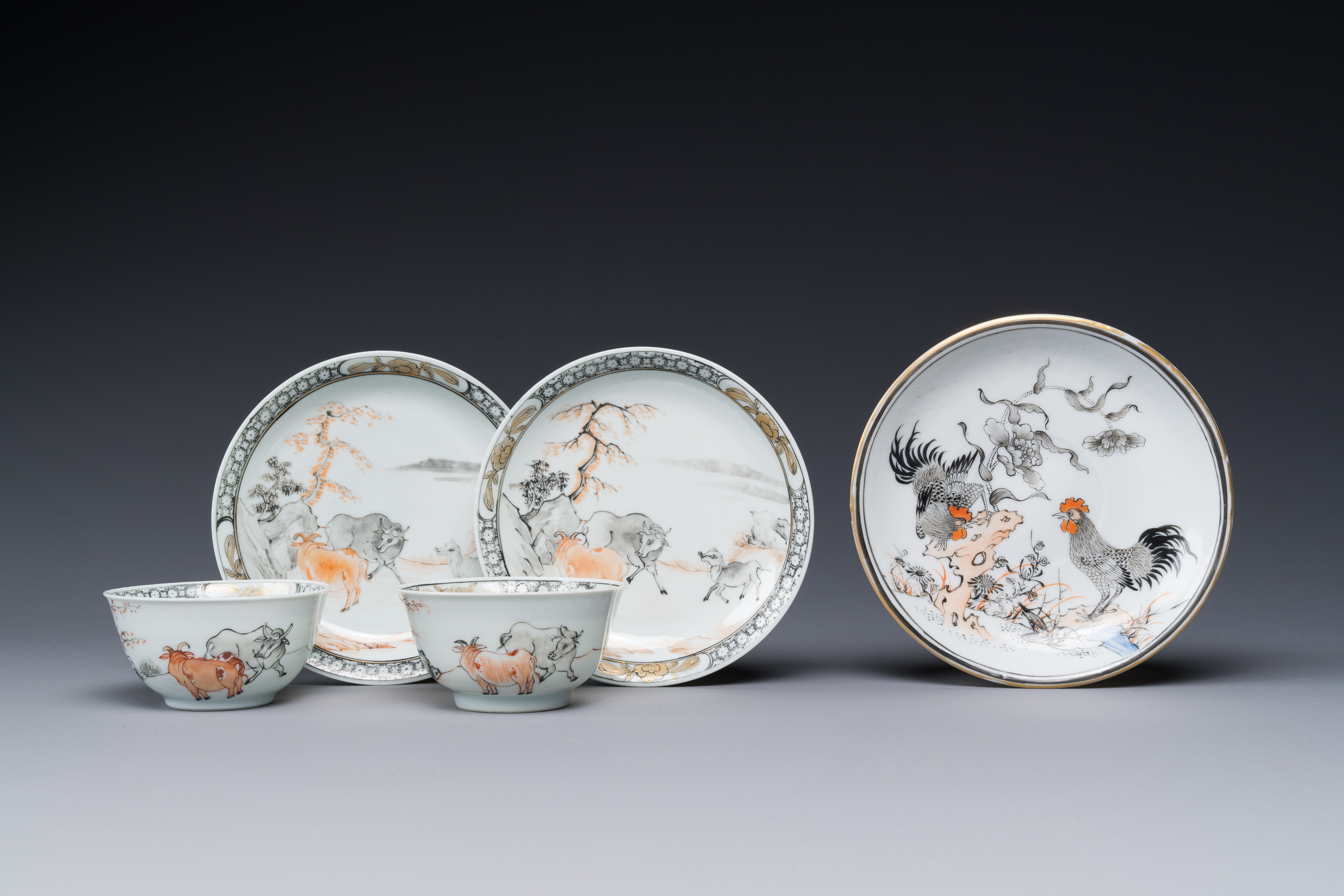 A pair of Chinese grisaille and iron-red 'buffalo' cups and saucers and a 'rooster' saucer, Yongzhen