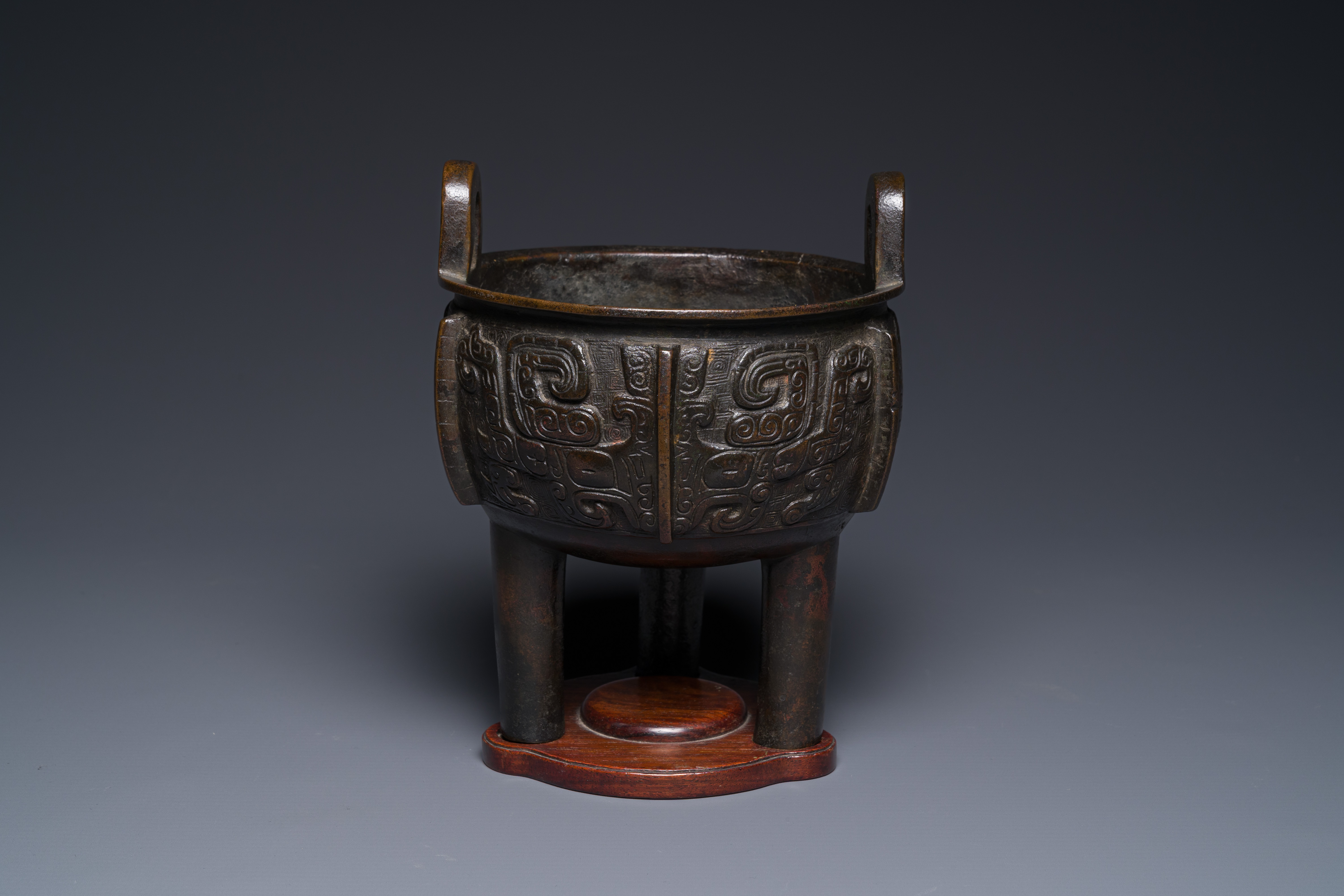 A Chinese archaistic bronze tripod censer on wooden stand, 'ding', Song/Ming