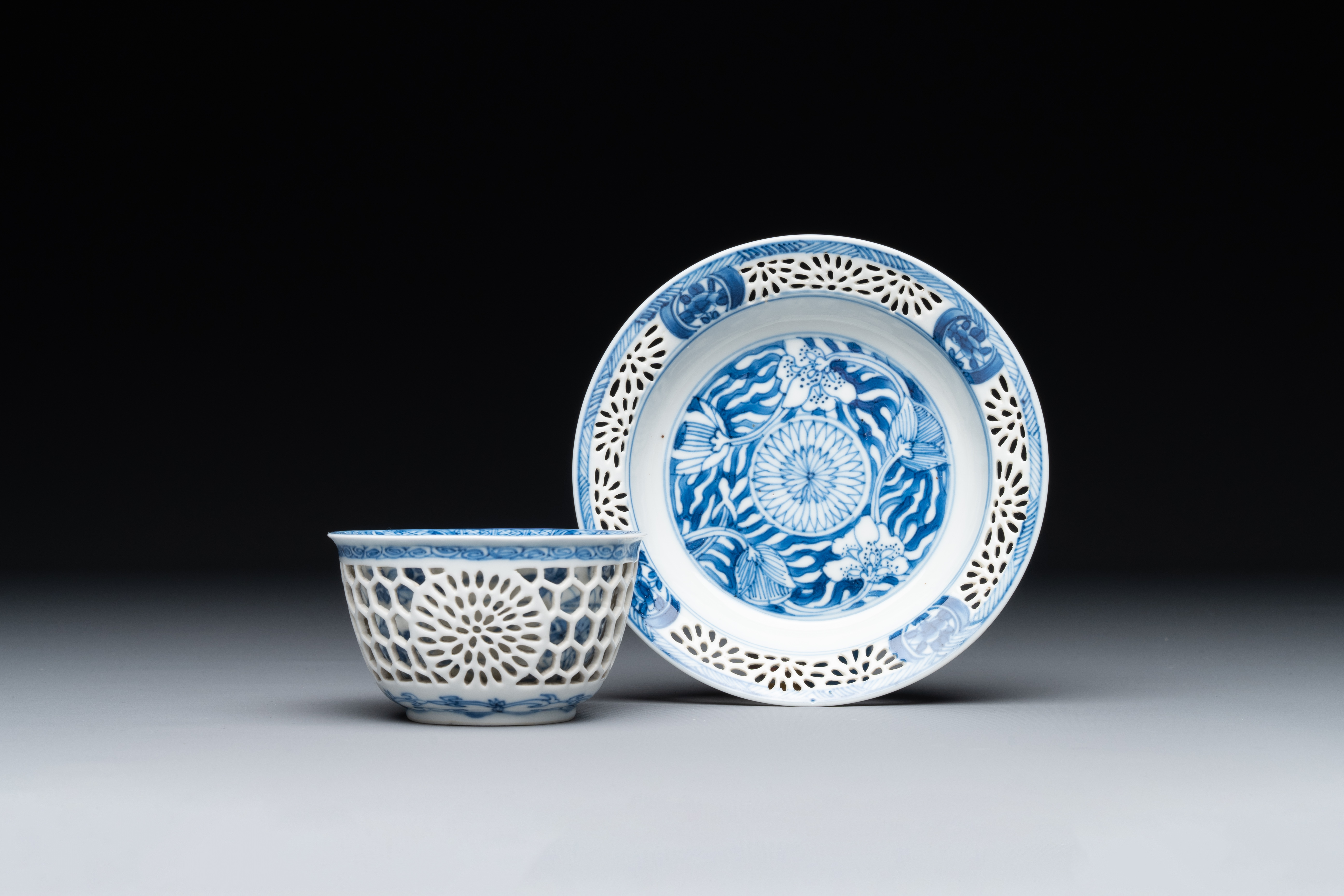 A Chinese blue and white reticulated double-walled cup and saucer, Kangxi