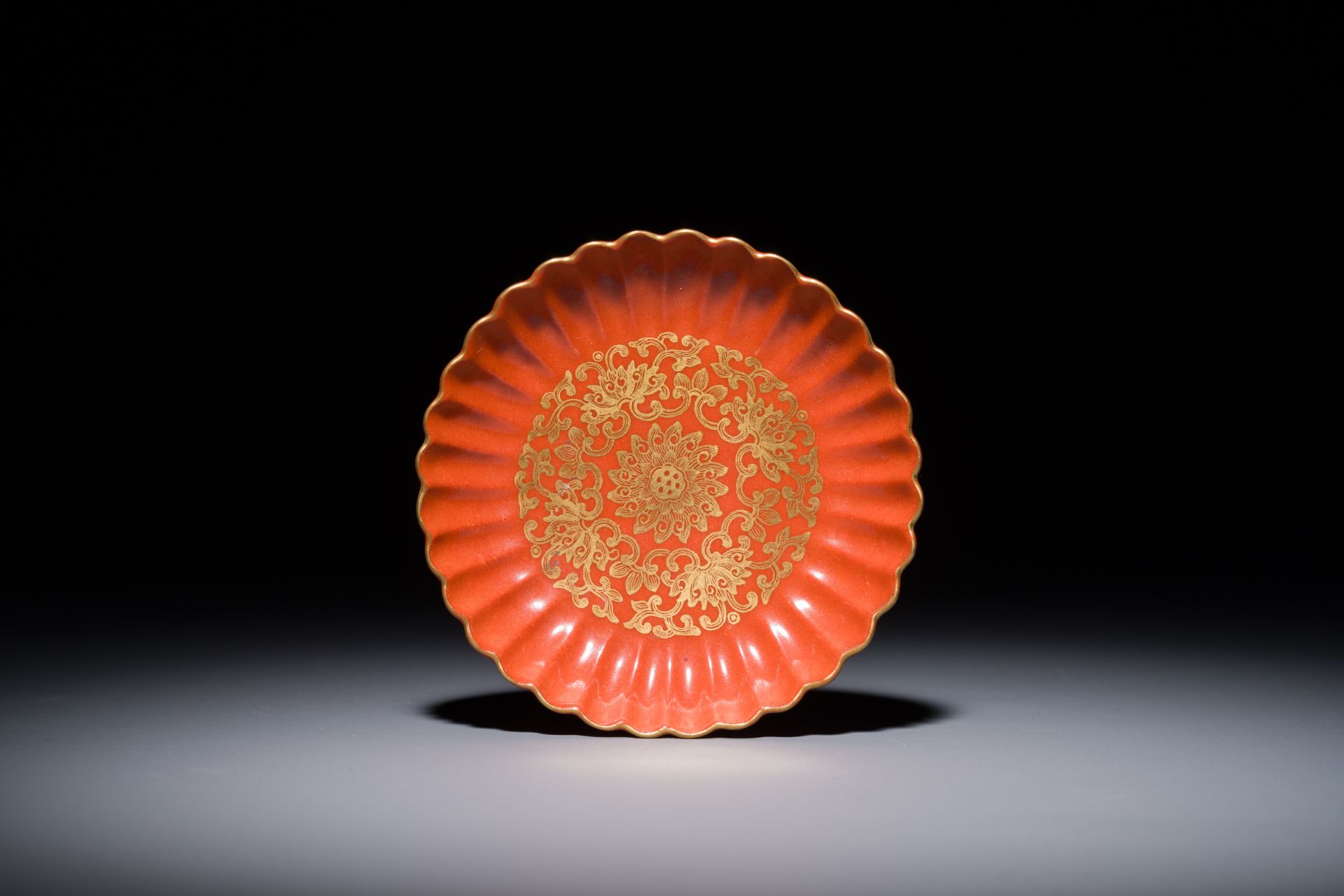 A Chinese coral-red-glazed gilt-decorated 'lotus scroll' saucer, Jiaqing mark, Republic