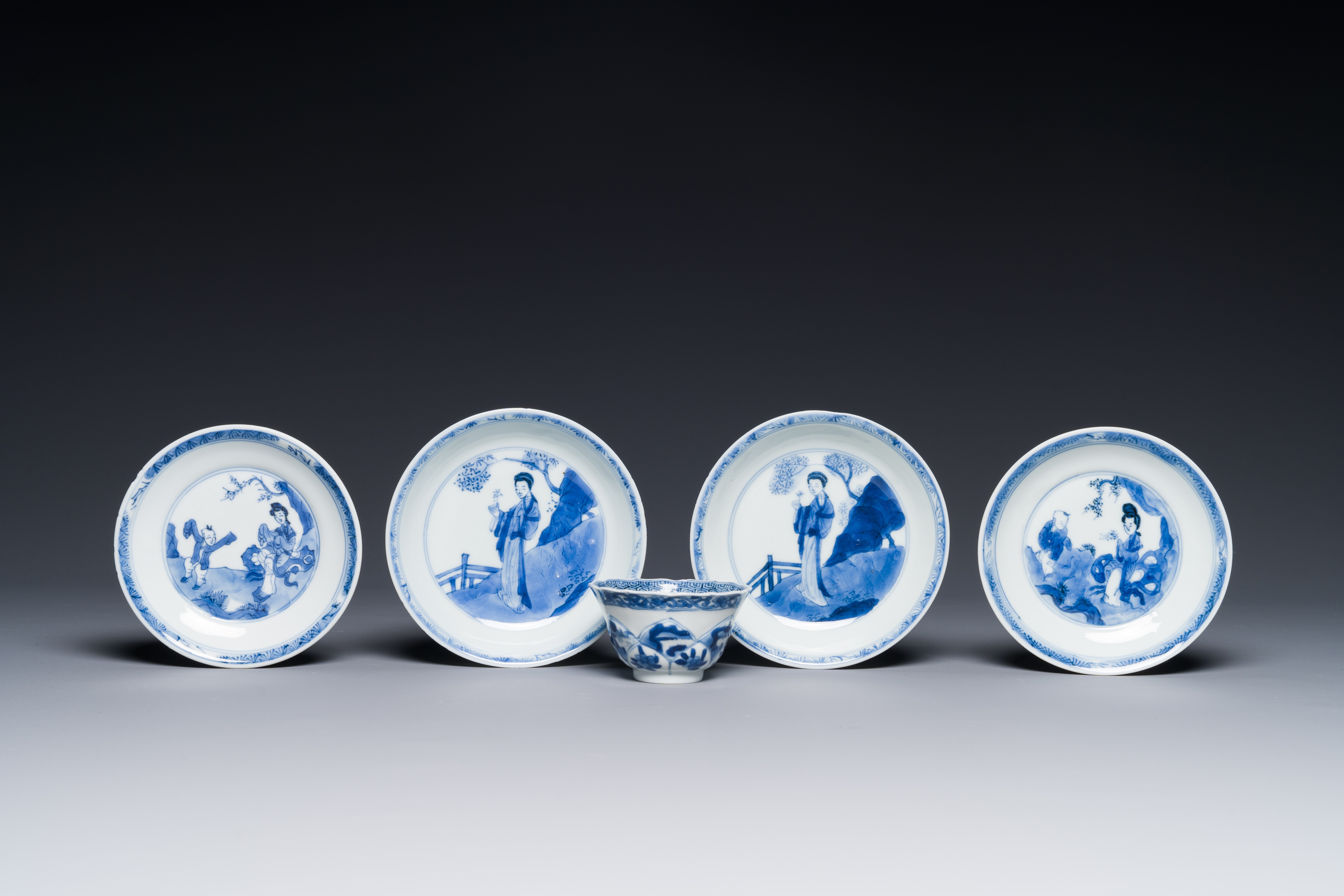 Four Chinese blue and white saucers and an 'erotic' cup, Kangxi