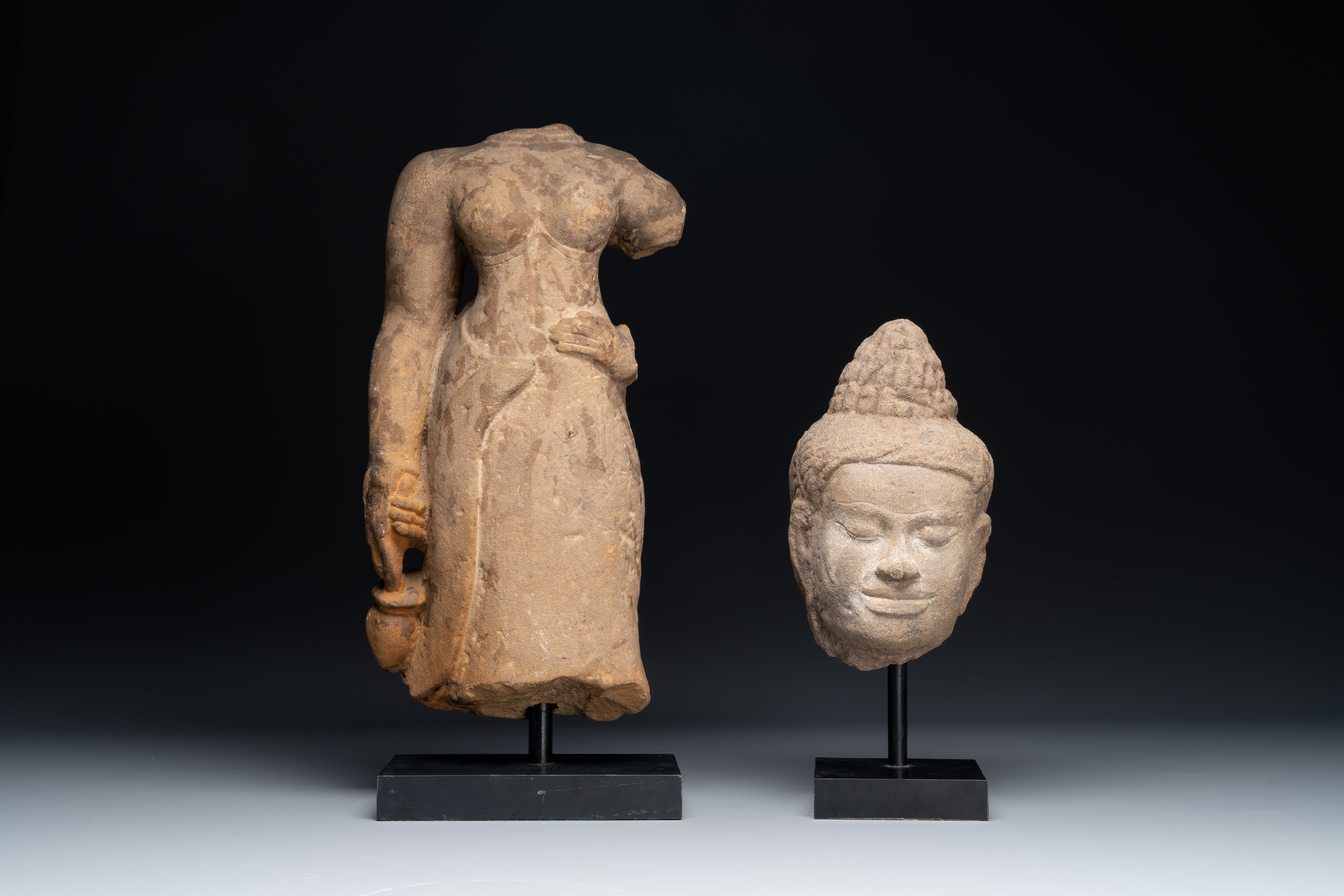 A sandstone female torso and a Buddha head, Cambodia, late Khmer period, 13/14th C.