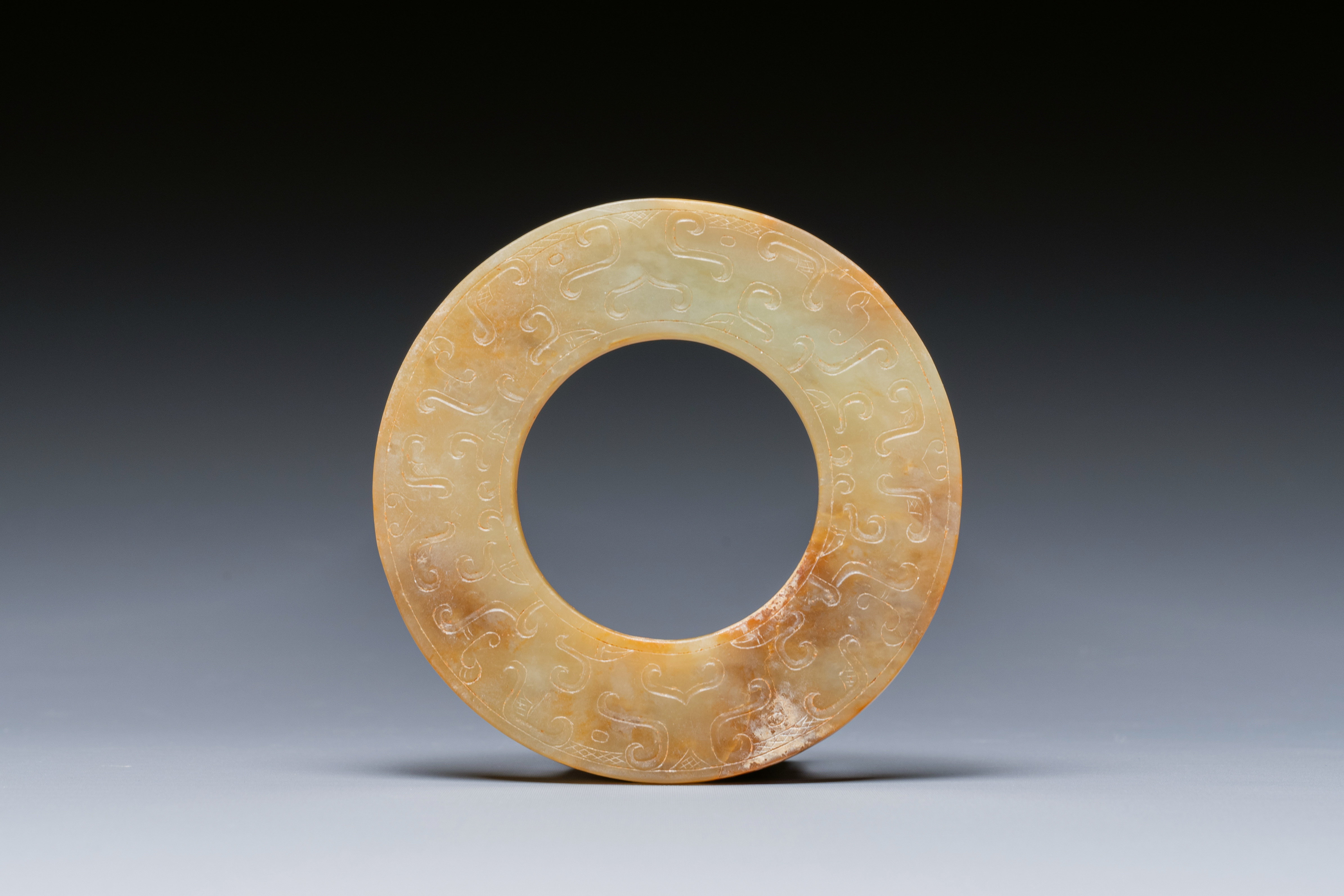 A Chinese celadon and russet jade 'bi' disc, probably Han