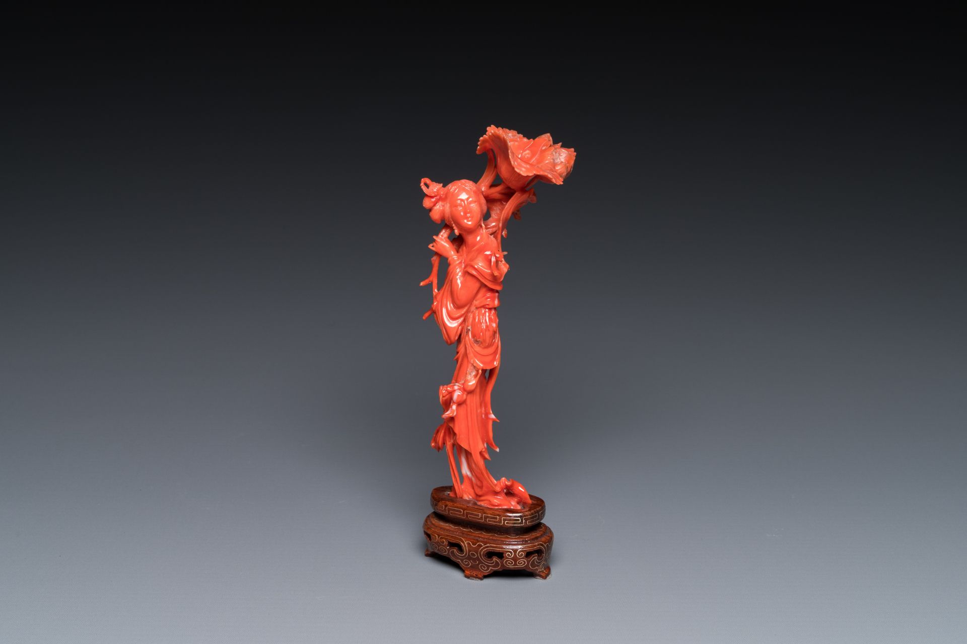 A Chinese red coral figure of a standing lady holding a flower, 19/20th C.