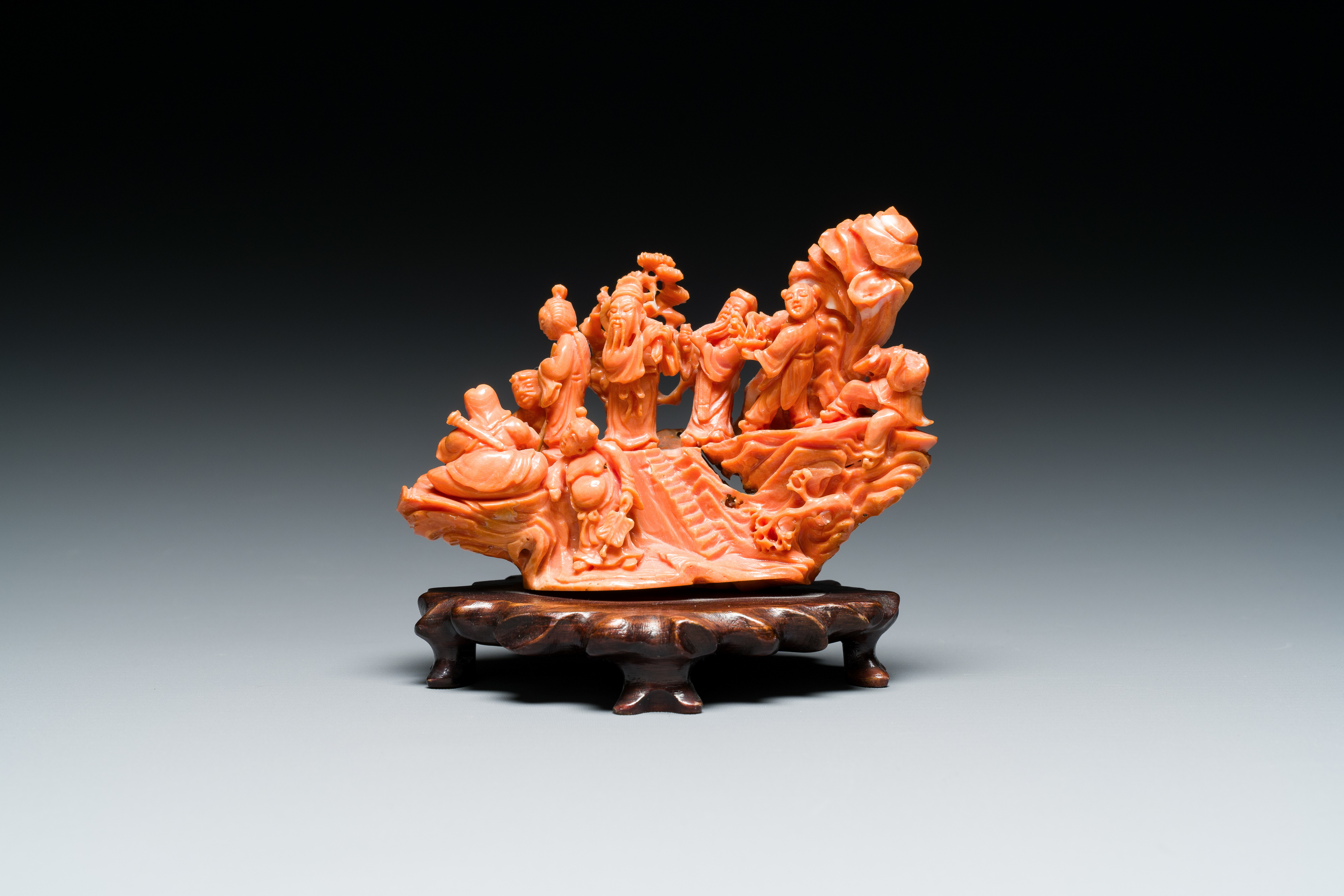 A Chinese red coral 'Eight Immortals' group on wooden stand, 19/20th C.