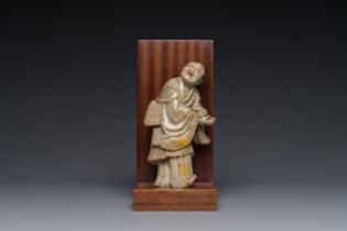 A Chinese partly polychromed soapstone figure on a wooden base, 18th C.