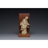 A Chinese partly polychromed soapstone figure on a wooden base, 18th C.