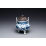 A Chinese blue and white tripod censer with floral design and a wooden cover, Ming