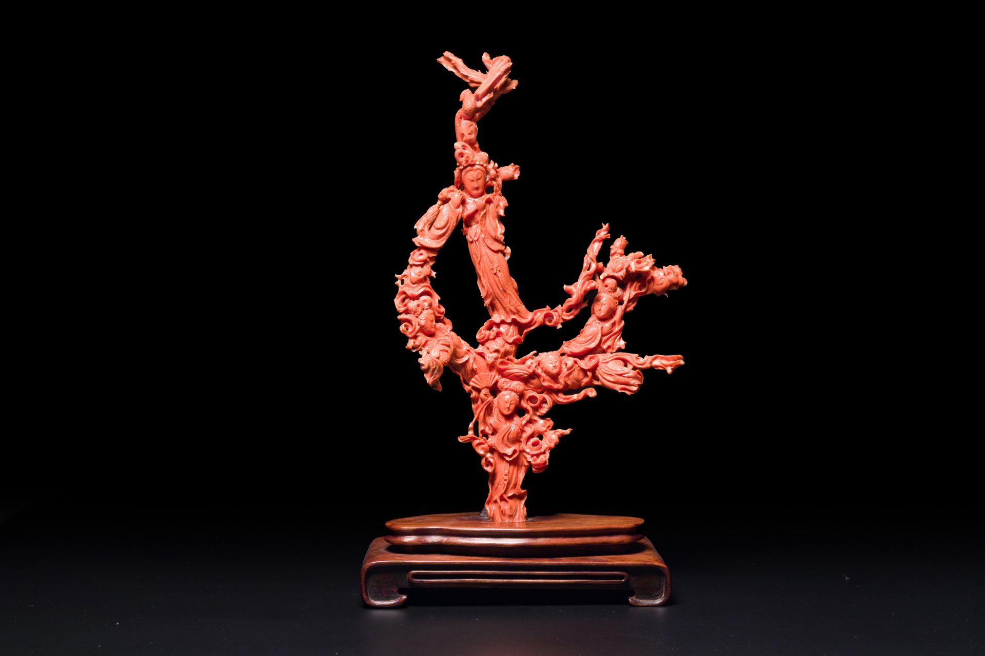 A large Chinese red coral group of female deities among clouds on wooden stand, 19/20th C.