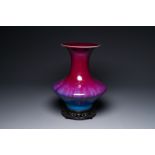 A Chinese flambe-glazed vase on a wooden base, 19th C.
