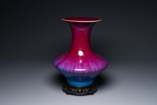 A Chinese flambe-glazed vase on a wooden base, 19th C.