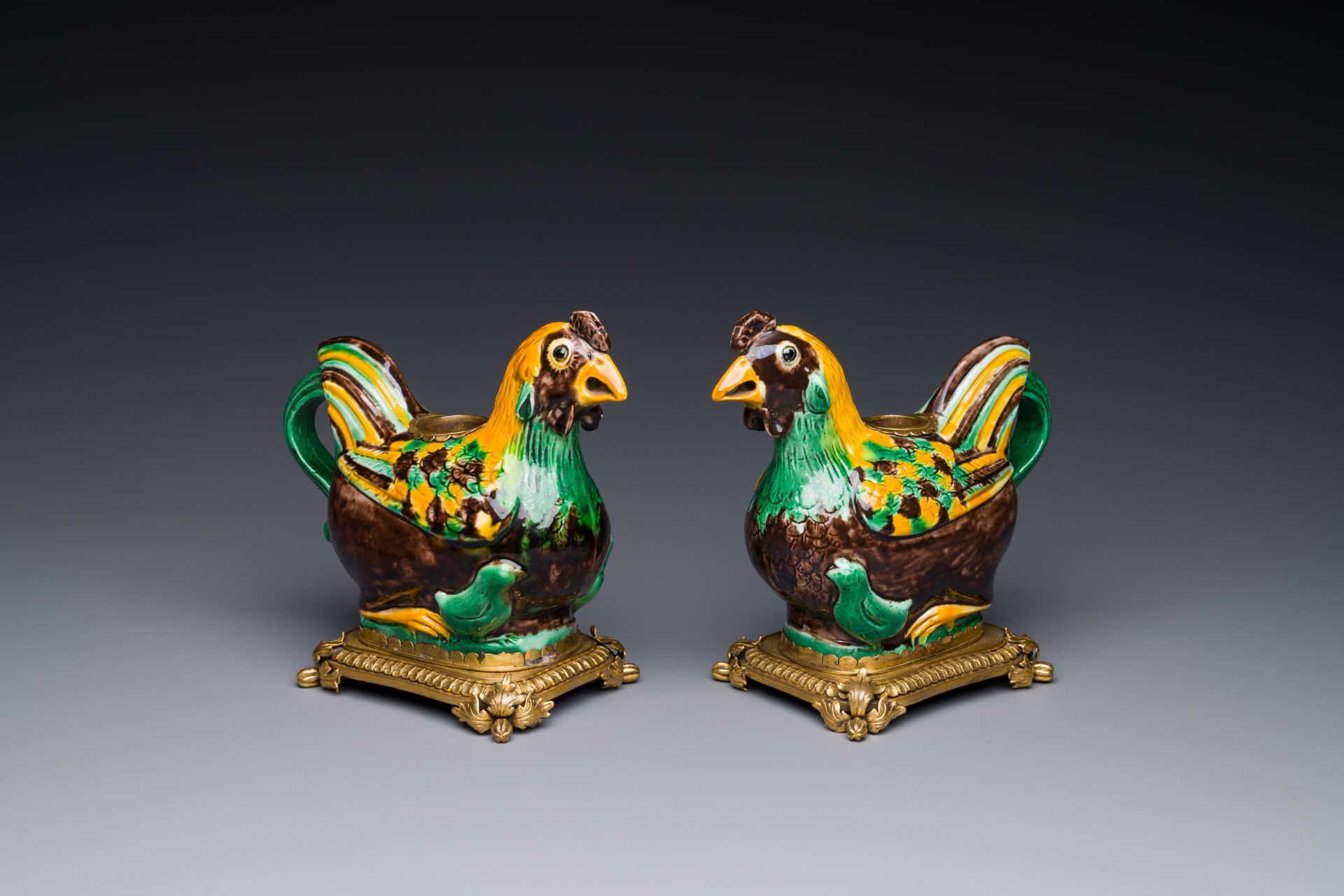 A pair of Chinese sancai-glazed chicken ewers mounted as candleholders with gilt bronze, Kangxi