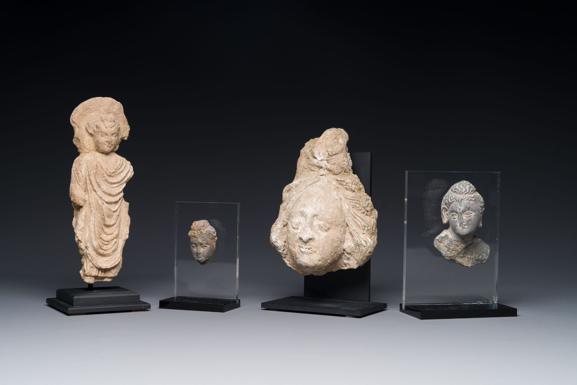 Two small Gandhara grey schist Bodhisattva heads, a stucco sculpture of Bodhisattva and a stucco fem