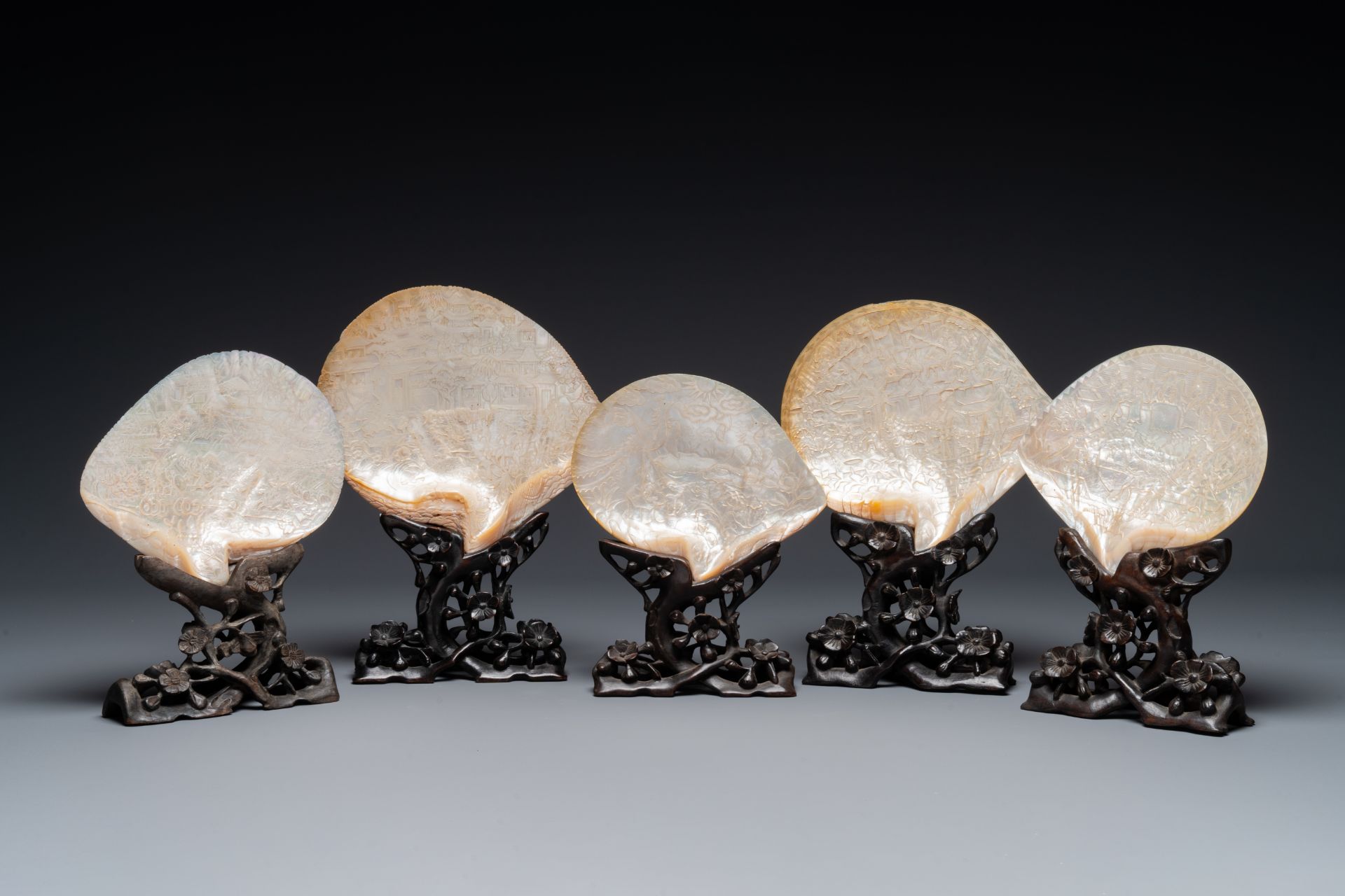 Five Chinese carved mother-of-pearl shells on wooden stands, Canton, 19th C.