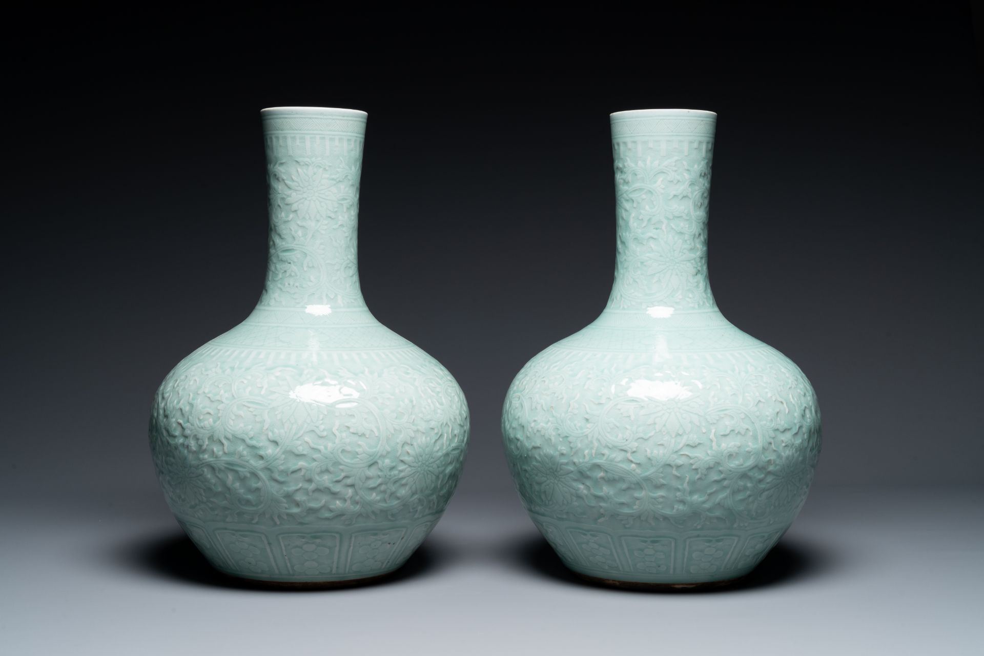 A pair of large Chinese monochrome celadon-glazed anhua 'lotus scrol' bottle vases, 19th C.