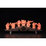 A set of seven Chinese red coral figures on wooden stand, 19/20th C.