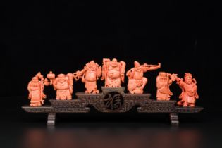 A set of seven Chinese red coral figures on wooden stand, 19/20th C.