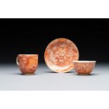 Two rare Chinese iron-red-decorated 'European scene' cups and a saucer, Qianlong