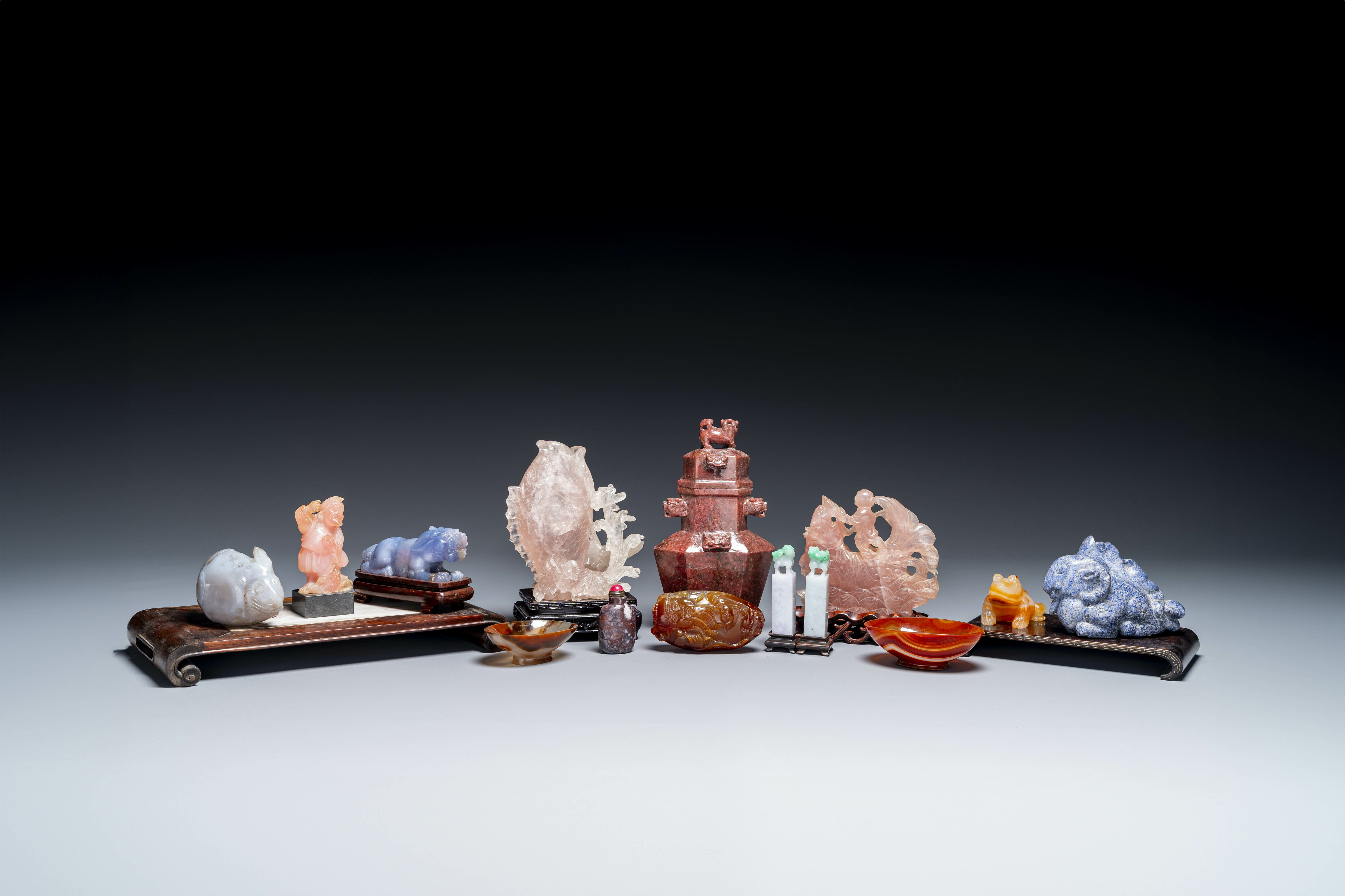 A group of Chinese carvings in lapis lazuli, pink quartz and other precious stones, with several sta