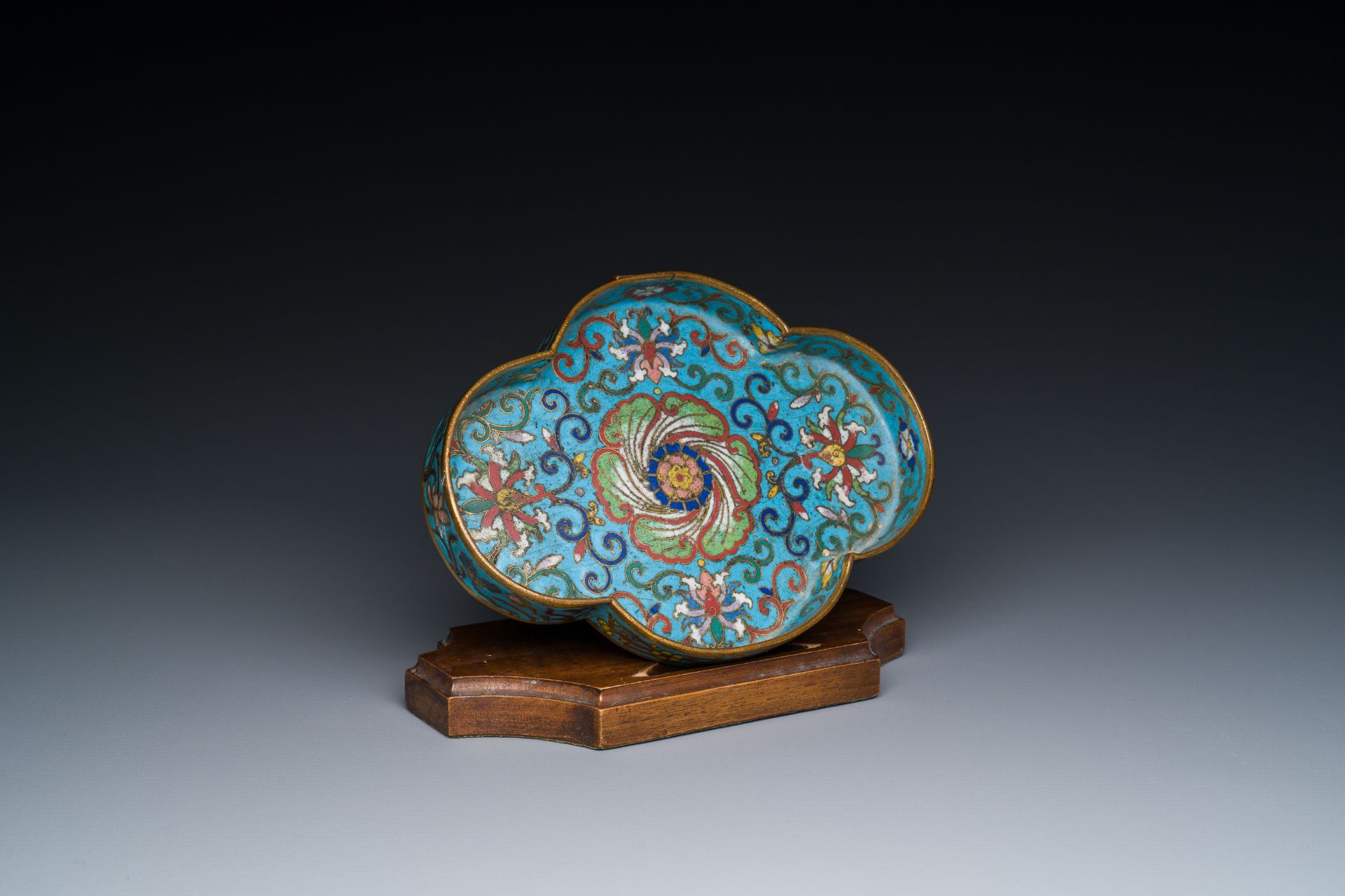 A Chinese quadrifoil cloisonne dish with floral design on wooden stand, Yongzheng
