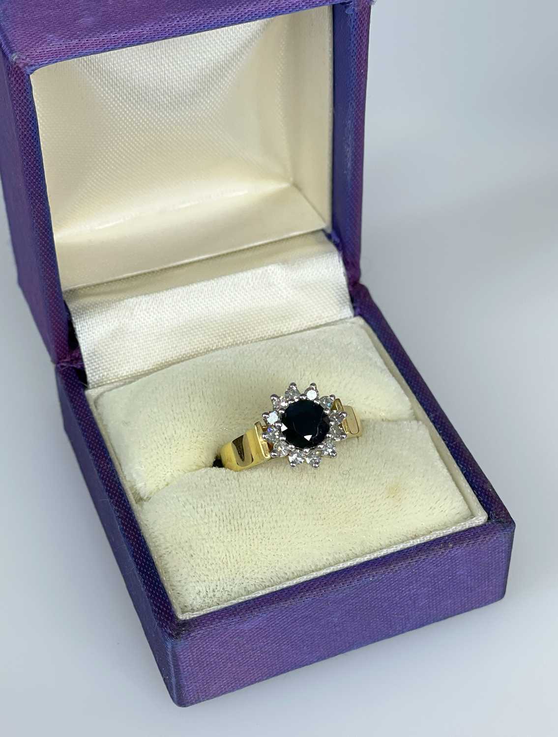 SAPPHIRE & DIAMOND HALO RING, round cushion cut dark cenral stone and 12 brilliant cut diamonds,