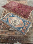 THREE EASTERN STYLE WOOLEN RUGS IN WORN CONDITIONS, comprising a larger rust ground example,