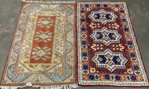 TWO EASTERN STYLE WOOLLEN RUGS, colourful red grounds, central repeating block pattern, one with