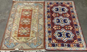 TWO EASTERN STYLE WOOLLEN RUGS, colourful red grounds, central repeating block pattern, one with