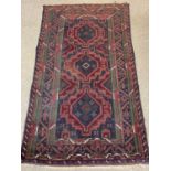 PERSIAN RED/BLUE GROUND HANDMADE WOOL RUG, triple medallion centre, geometric border, 192 x 113cms